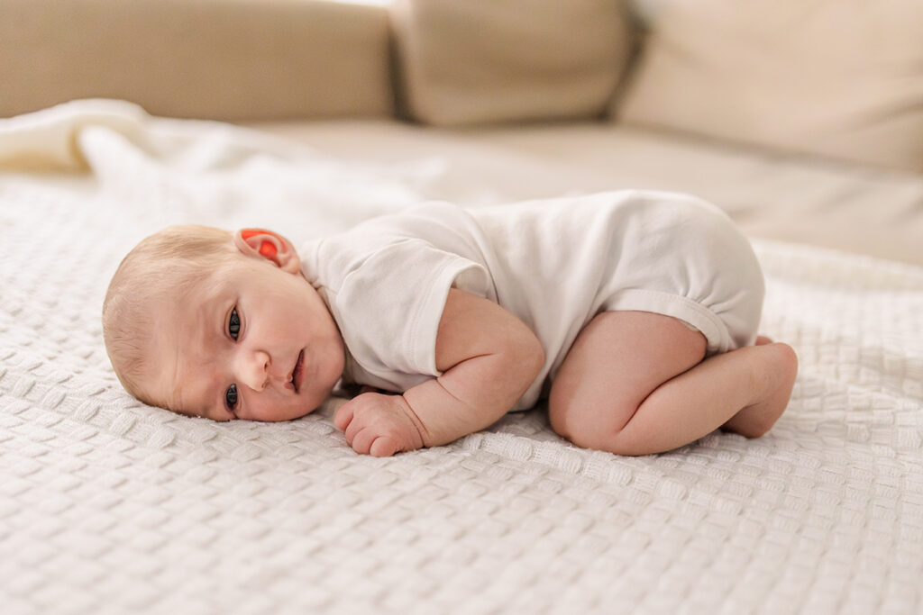 a baby lying on its belly on a white blanket
