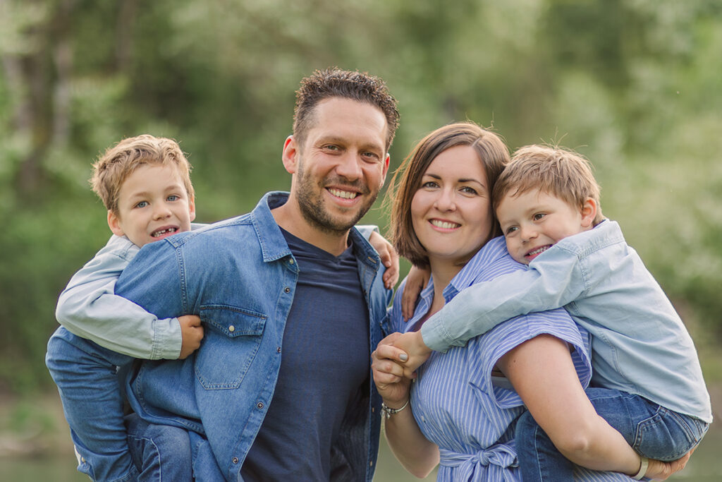Familienshooting an der Aare mit Eltern die ihr Kind Huckepack tragen