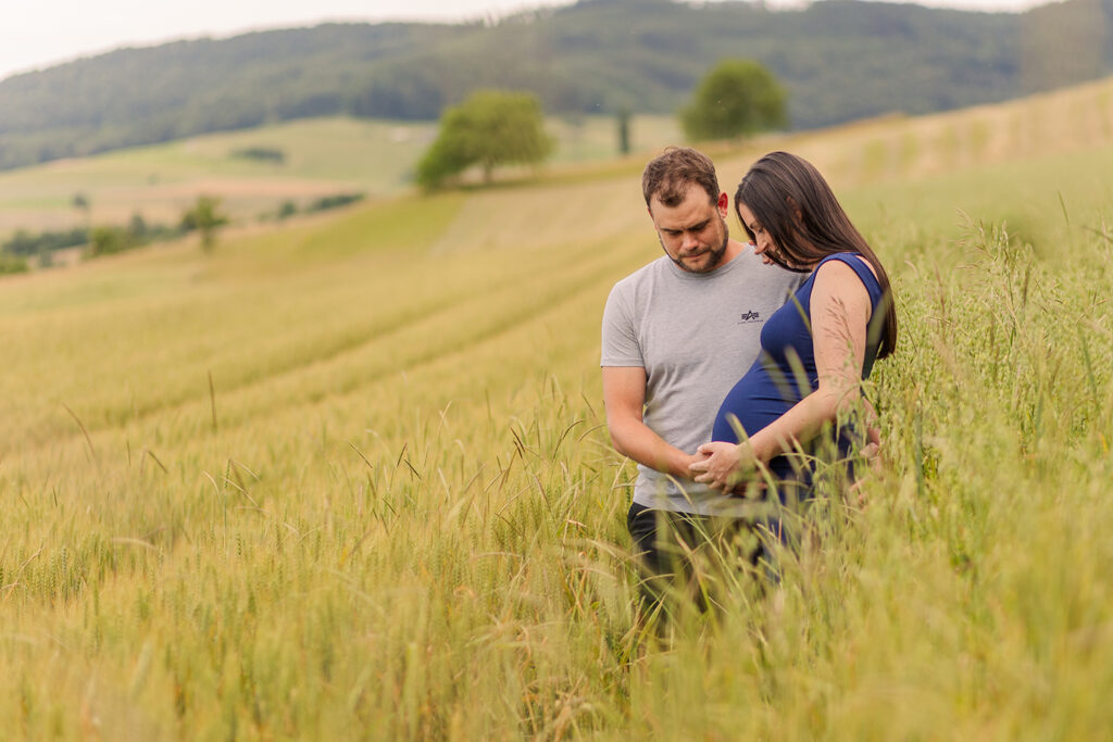 Schwangere und Mann im Cornfeld betrachten den Babybauch